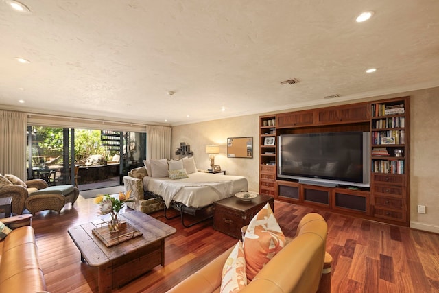 living room with crown molding, dark wood-type flooring, and built in shelves