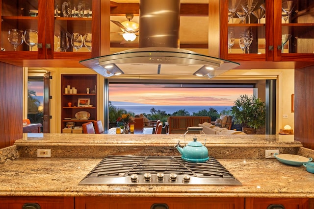 kitchen featuring light stone countertops, stainless steel gas cooktop, and island exhaust hood