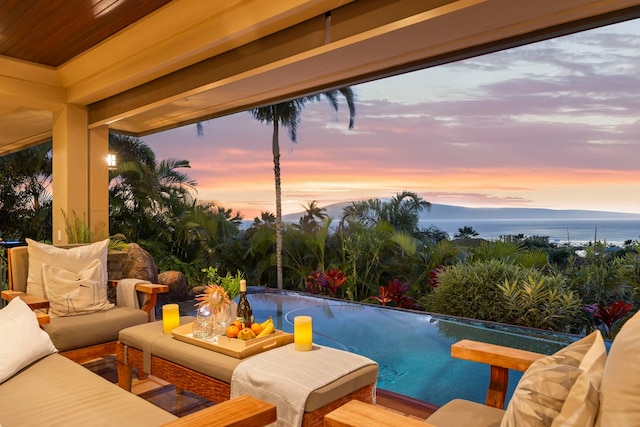 pool at dusk featuring an outdoor hangout area and a water view