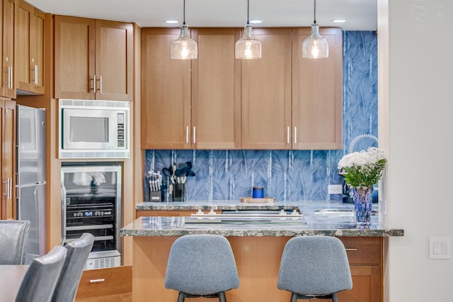 3200 Wailea Alanui Dr Unit 2105, Kihei, HI 96753 - kitchen featuring beverage cooler, stainless steel refrigerator, built in microwave, dark stone counters, and a breakfast bar area