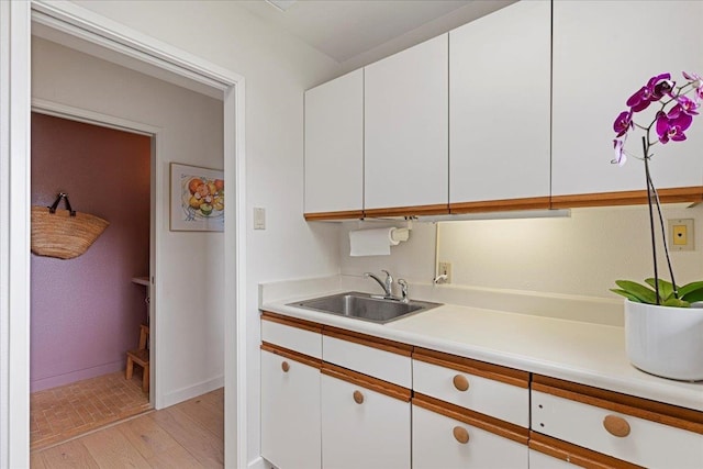 kitchen with white cabinetry, light hardwood / wood-style floors, and sink