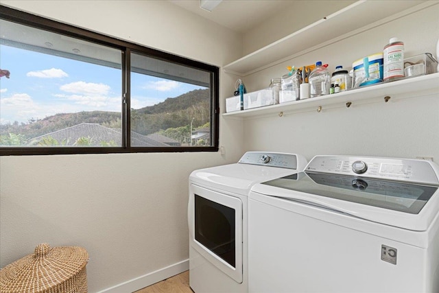 washroom with washing machine and clothes dryer, a mountain view, and light hardwood / wood-style flooring