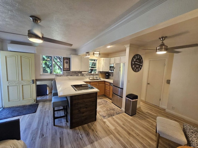 kitchen with stainless steel appliances, a peninsula, a sink, a kitchen breakfast bar, and an AC wall unit