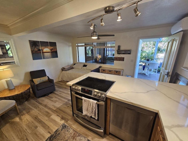 kitchen featuring a wall unit AC, light wood-style flooring, light stone counters, stainless steel electric stove, and crown molding