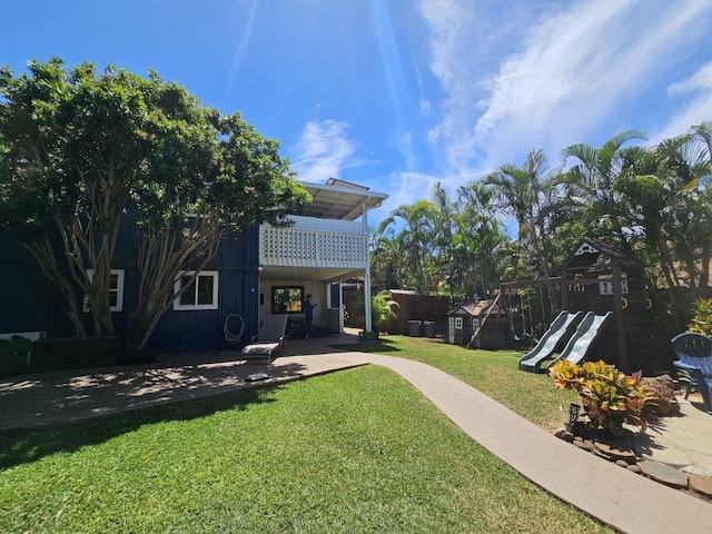 rear view of property with a patio, a lawn, a playground, and fence