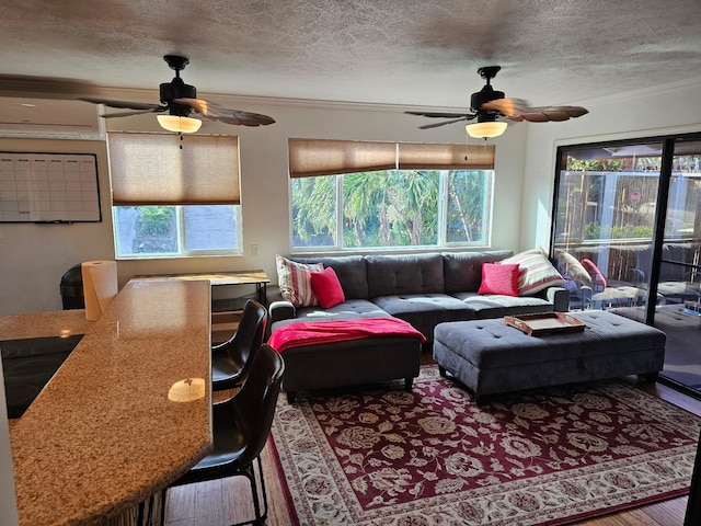 living area featuring a textured ceiling, a wall mounted AC, and a ceiling fan