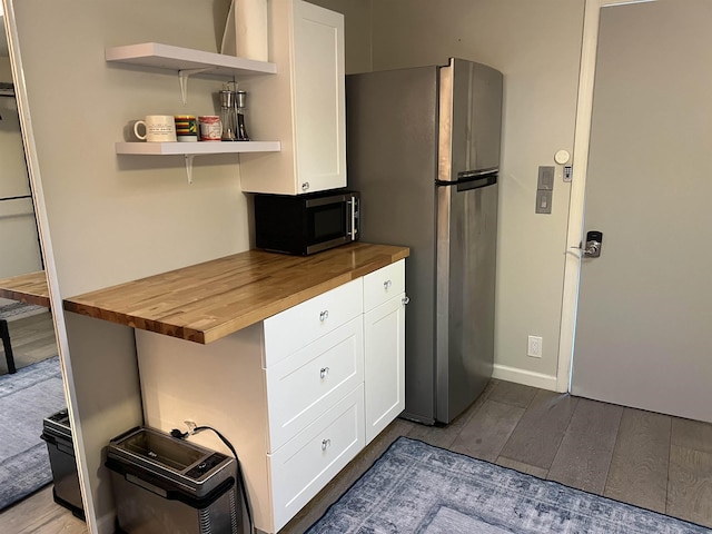 kitchen featuring stainless steel appliances, wood finished floors, wood counters, and white cabinetry