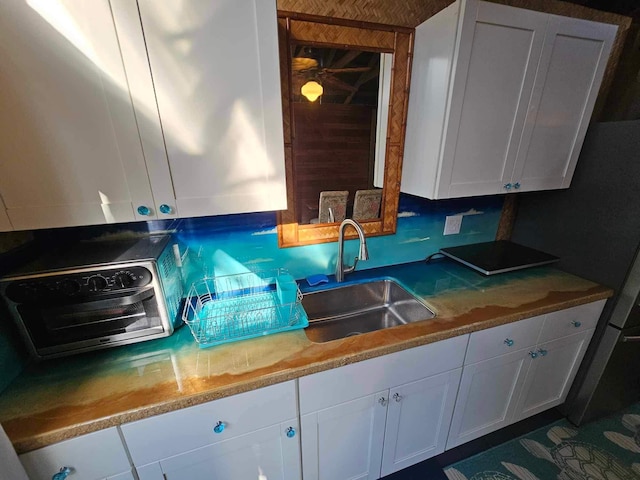 kitchen featuring a toaster, white cabinetry, and a sink