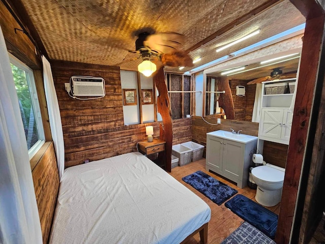 bedroom with a wall unit AC, a sink, and wooden walls