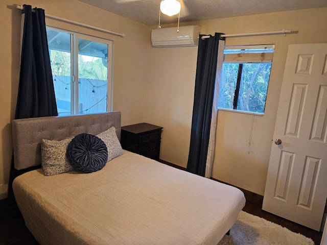 bedroom with access to exterior, multiple windows, dark wood-style flooring, and an AC wall unit