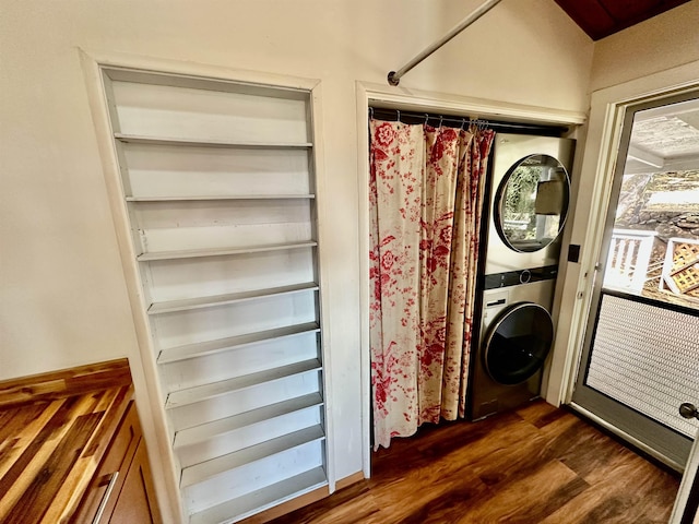 laundry area with dark hardwood / wood-style flooring and stacked washer and clothes dryer