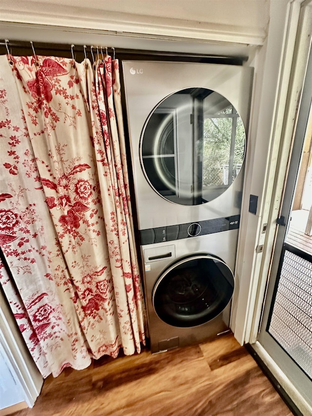 clothes washing area featuring stacked washer and dryer and hardwood / wood-style floors