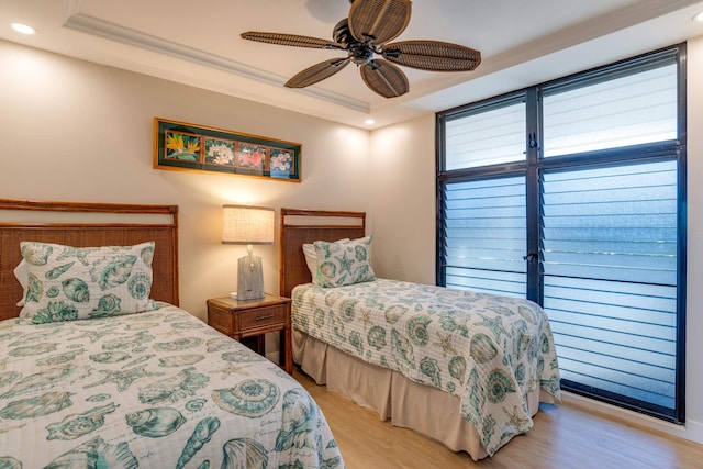 bedroom featuring a tray ceiling, ceiling fan, and light hardwood / wood-style flooring