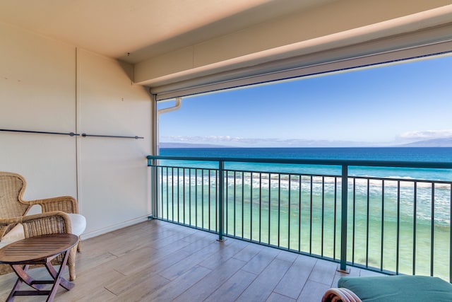 balcony featuring a view of the beach and a water view