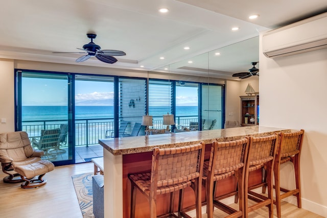 bar featuring plenty of natural light, a water view, and light hardwood / wood-style floors