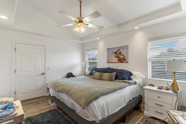 bedroom with lofted ceiling, a tray ceiling, ceiling fan, and hardwood / wood-style floors