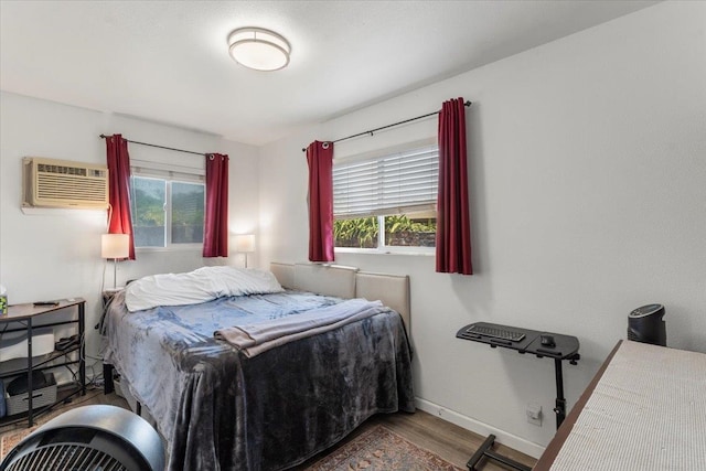 bedroom featuring hardwood / wood-style flooring, multiple windows, and a wall mounted AC