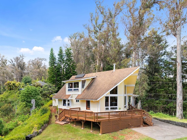 1733 Piiholo Rd, Makawao, HI 96768 - view of front of home with solar panels, a wooden deck, a shingled roof, and view of scattered trees