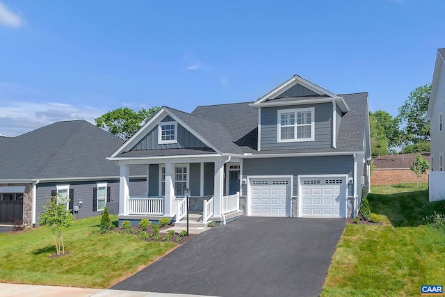 view of front of house with a porch, a garage, and a front lawn