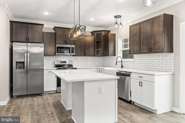 kitchen featuring a kitchen island, glass insert cabinets, stainless steel appliances, light countertops, and white cabinetry