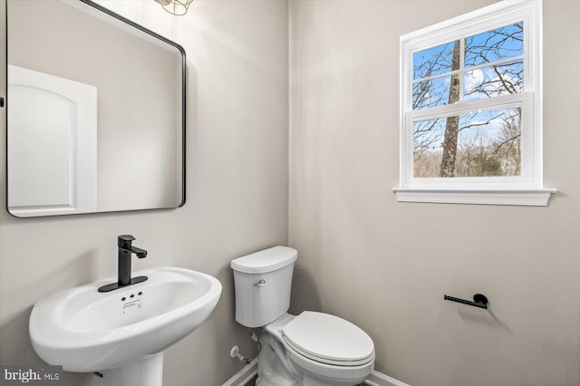 bathroom featuring toilet, baseboards, and a sink