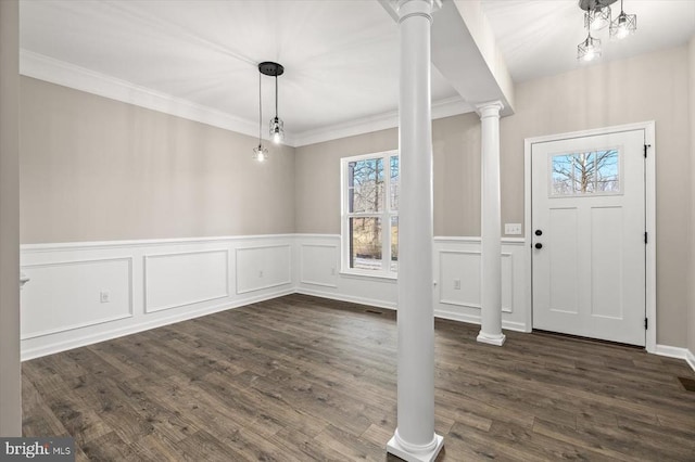 entrance foyer with crown molding, dark wood finished floors, decorative columns, a decorative wall, and wainscoting