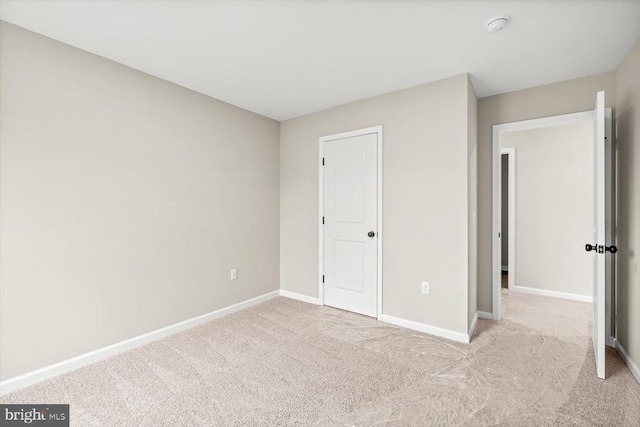 unfurnished bedroom featuring light carpet and baseboards