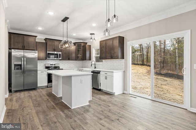 kitchen featuring dark brown cabinetry, a center island, hanging light fixtures, stainless steel appliances, and light countertops