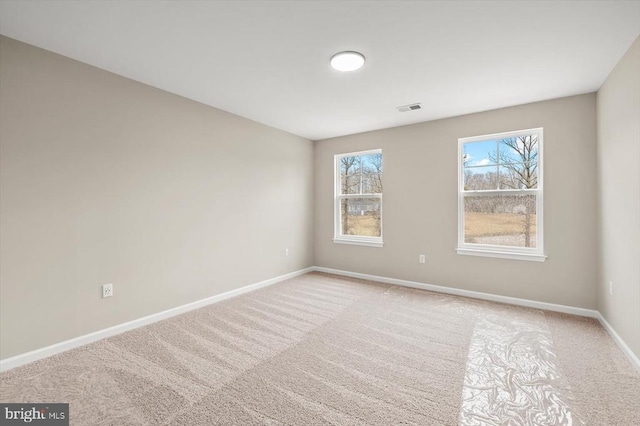 unfurnished room with light colored carpet, visible vents, and baseboards