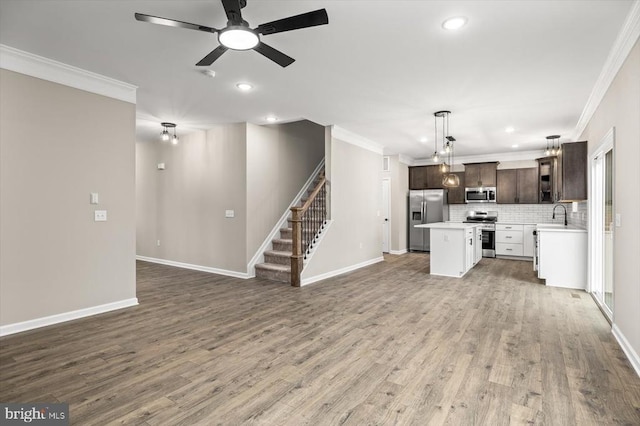 unfurnished living room with ornamental molding, dark wood-style flooring, and stairway