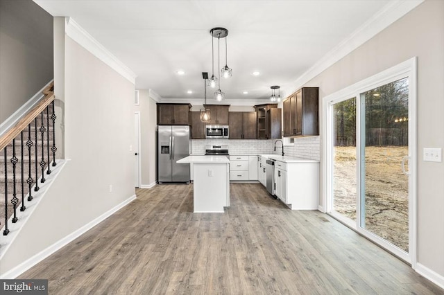 kitchen featuring dark brown cabinetry, stainless steel appliances, a kitchen island, light countertops, and pendant lighting