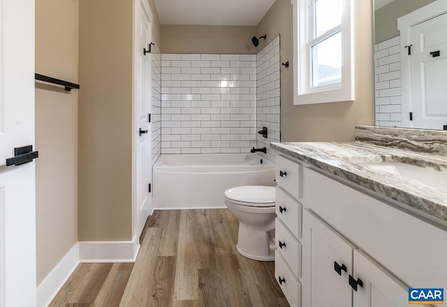 full bathroom featuring tiled shower / bath combo, vanity, hardwood / wood-style floors, and toilet