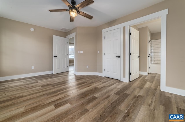 unfurnished bedroom with hardwood / wood-style flooring, ensuite bathroom, and ceiling fan