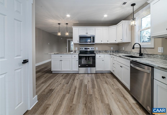 kitchen with white cabinetry, appliances with stainless steel finishes, sink, and pendant lighting