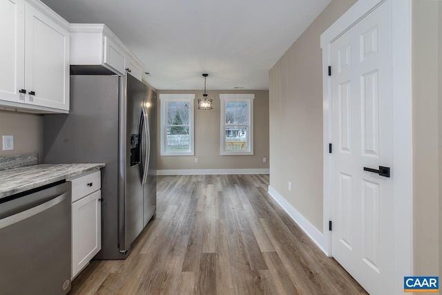 kitchen featuring white cabinetry, appliances with stainless steel finishes, light stone countertops, and pendant lighting