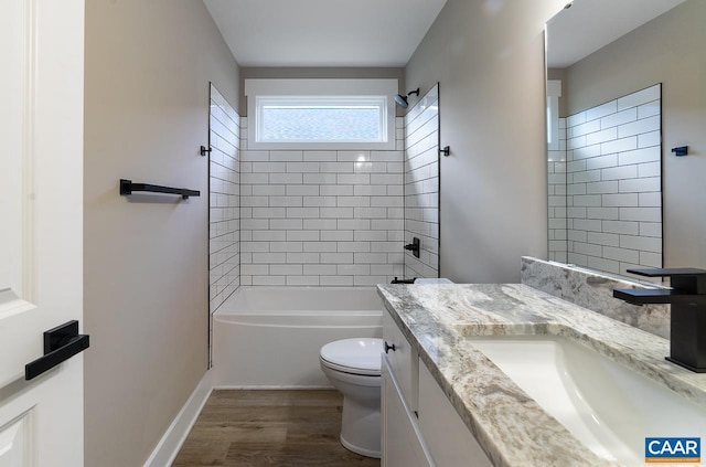 full bathroom featuring vanity, hardwood / wood-style floors, tiled shower / bath, and toilet