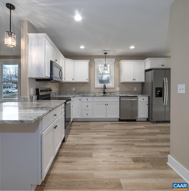 kitchen with sink, white cabinetry, decorative light fixtures, stainless steel appliances, and light stone countertops