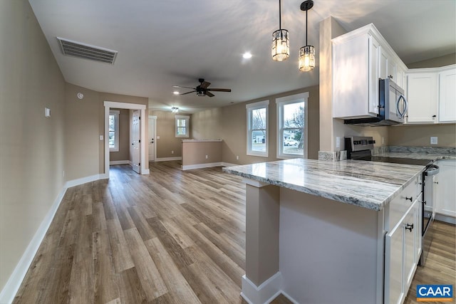 kitchen with appliances with stainless steel finishes, hanging light fixtures, light stone countertops, white cabinets, and kitchen peninsula