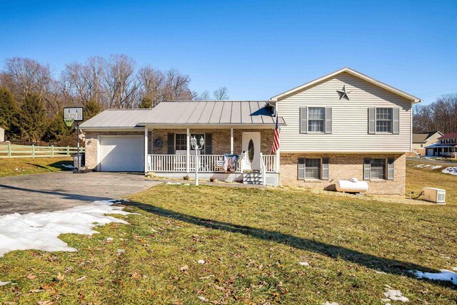 split level home featuring a porch, a garage, and a front yard