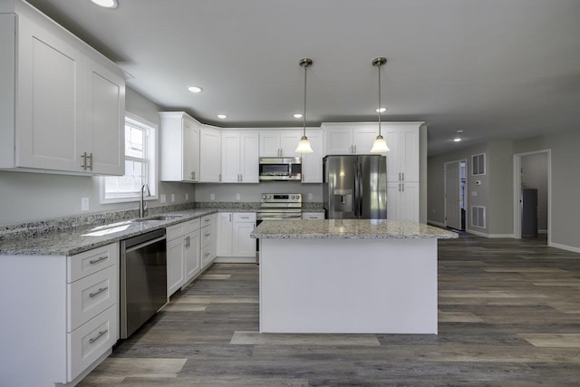 kitchen featuring white cabinetry, decorative light fixtures, a center island, and appliances with stainless steel finishes