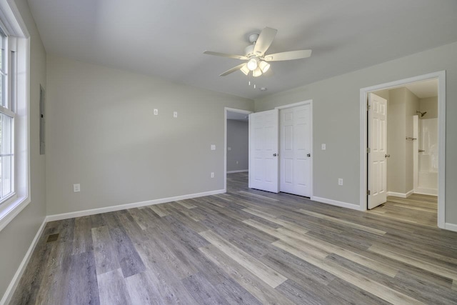 unfurnished bedroom with ensuite bath, light hardwood / wood-style floors, and ceiling fan