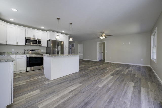 kitchen with stainless steel appliances, white cabinetry, pendant lighting, and light wood-type flooring