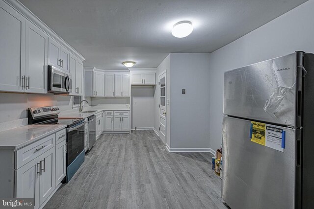 kitchen featuring sink, stainless steel appliances, light hardwood / wood-style floors, and white cabinets