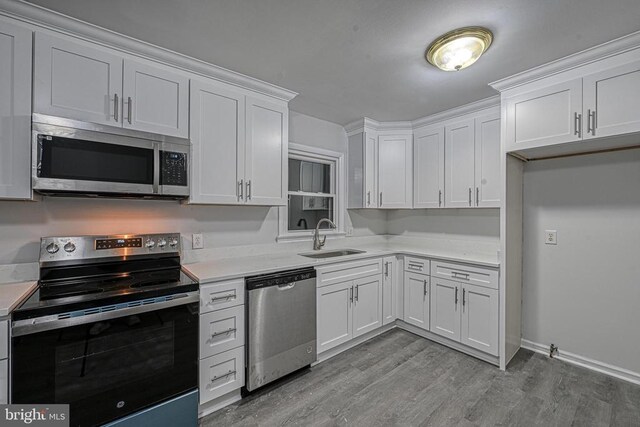 kitchen with stainless steel appliances, sink, white cabinets, and light wood-type flooring