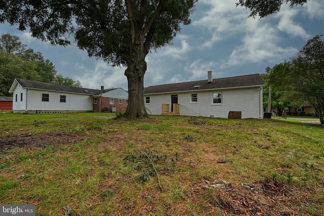 rear view of property featuring central air condition unit and a lawn