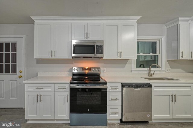 kitchen with stainless steel appliances, hardwood / wood-style flooring, sink, and white cabinets