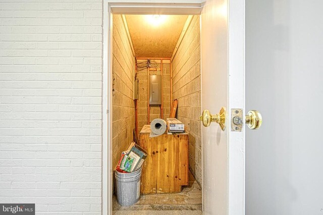 corridor featuring electric panel and brick wall