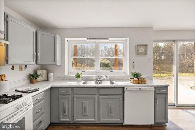 kitchen with white appliances, dark wood-style floors, light countertops, gray cabinetry, and a sink