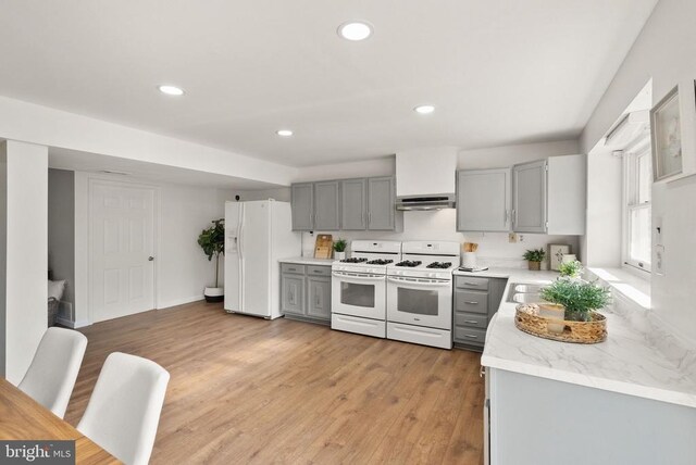 kitchen with white appliances, under cabinet range hood, gray cabinets, and light wood finished floors