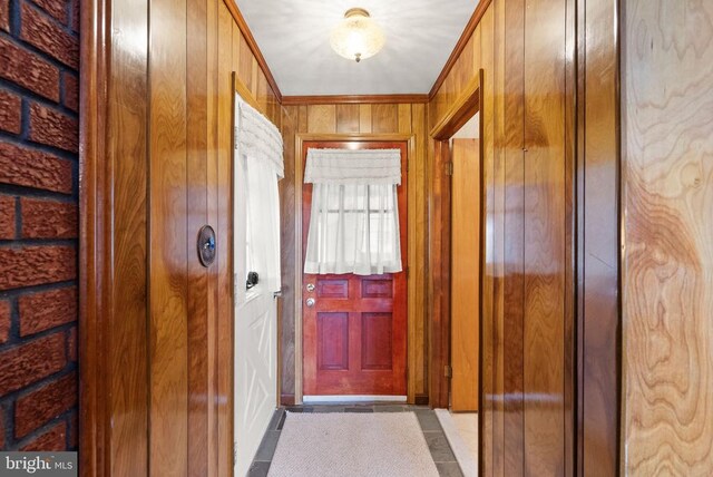 entryway with wood walls and crown molding